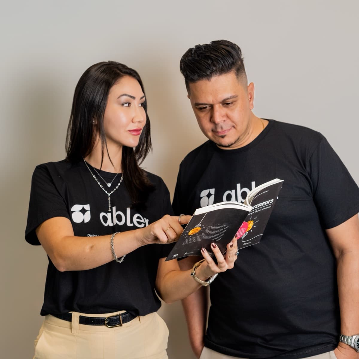 Duas pessoas do time abler lendo juntas um livro sobre empreendedorismo